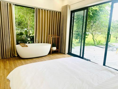 een slaapkamer met een bad en een groot raam bij Solmist Villa in Hòa Bình
