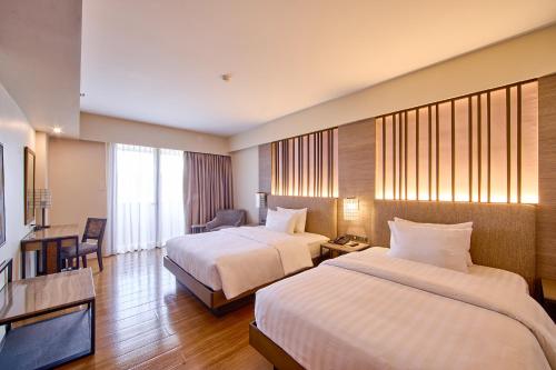 a hotel room with two beds and a television at The Aurora Subic Hotel Managed By HII in Olongapo