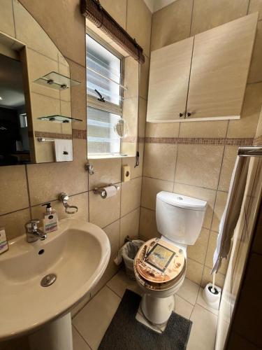 a bathroom with a sink and a toilet with a book on it at Amakhaya Lodge in Cape Town