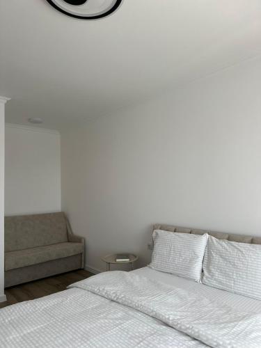 a white bedroom with a bed and a couch at White loft ЖК Престиж СВІТЛО ЦІЛОДОБОВО in Ternopil