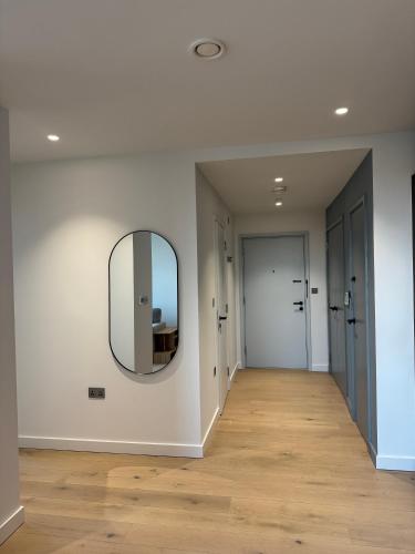 a hallway with a mirror and white walls and wooden floors at 02 Arena, Thames Riverside Retreat in London
