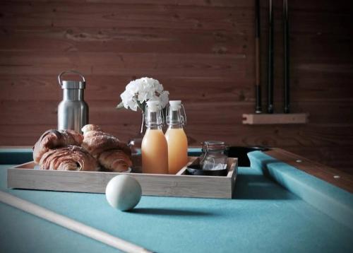 ein Billardtisch mit einem Tablett mit Donuts und Orangensaft in der Unterkunft Duplex accès jacuzzi illimité Z in Villedieu-les-Poëles