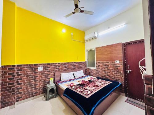 Cama en habitación con pared amarilla en shri radha ji guest House, en Vrindāvan