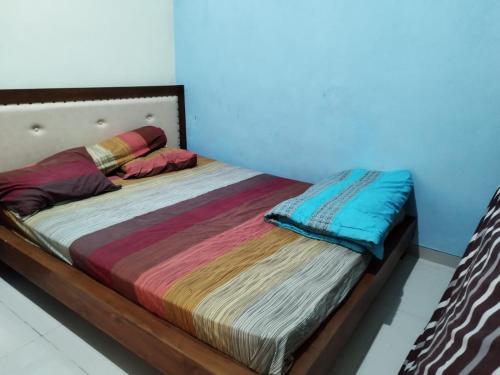 a bed with colorful blankets and pillows on it at Villa Kusuma Pinus M10 in Batu