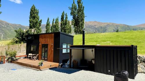 a small black house with a porch and a deck at Grace & Rose in Gibbston