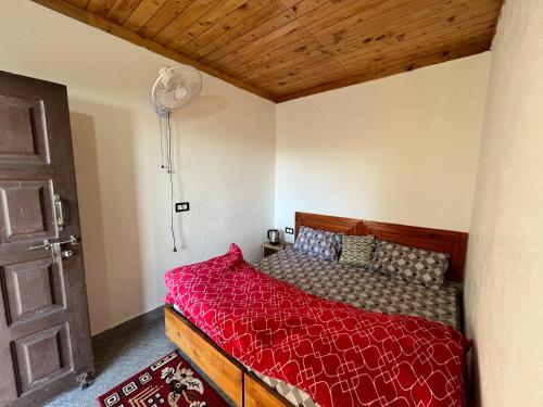 a bedroom with a bed with a red comforter at Sawra Homestay in Chakrāta