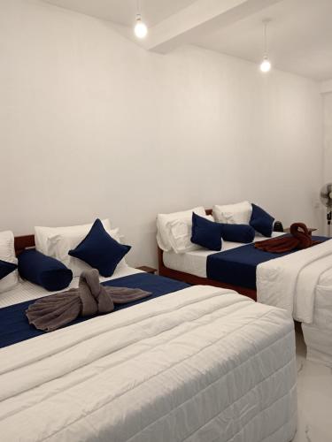 a room with three beds with blue and white pillows at Camellia Guest Inn in Ella