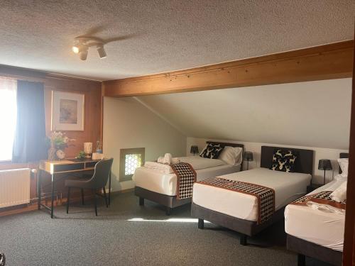 a hotel room with two beds and a desk at Sonne in Klosters