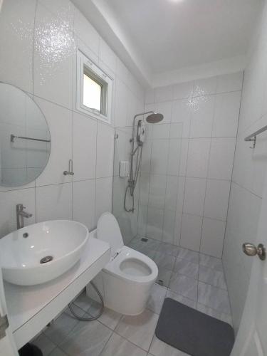 a white bathroom with a sink and a toilet at ม่อนคูณตะวันฮิลล์ลอดจ์ in Ban Tai