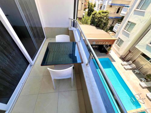 Un balcón con una mesa y una silla junto a una piscina. en Cemal Bey Hotel, en Alanya