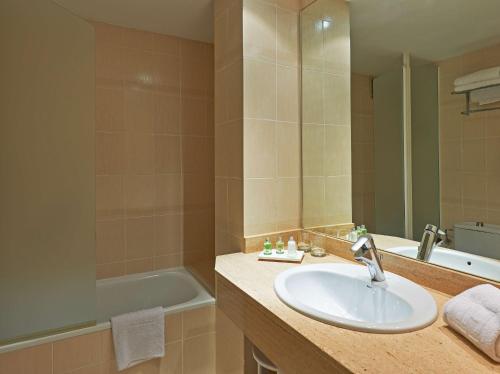 a bathroom with a sink and a bath tub at NH Sport in Zaragoza