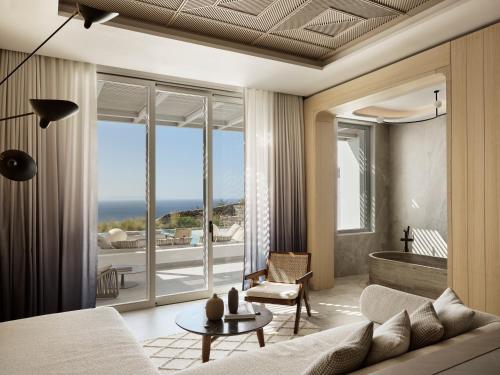 Deos Mykonos - A Myconian Collection Hotel في مدينة ميكونوس: غرفة معيشة بها أريكة وطاولة