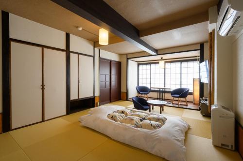 a bedroom with a bed with two chairs and a table at Koyado Enn in Toyooka