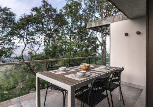a table and chairs on the balcony of a house at LohonoStays Amani Villa 10A in Coonoor