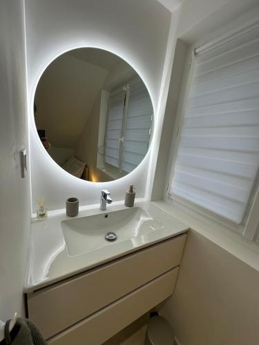 a white bathroom with a sink and a mirror at Appartement cosy 2 chambres in Jougne