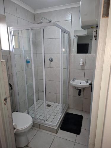 a bathroom with a shower and a toilet and a sink at Grace Villas 1 in East London