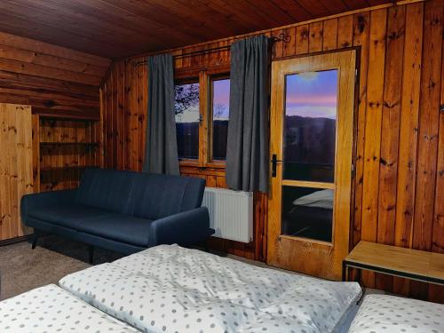 een slaapkamer met een bed, een bank en een raam bij Chata v Kamenném Přívozu in Kamenný Přívoz