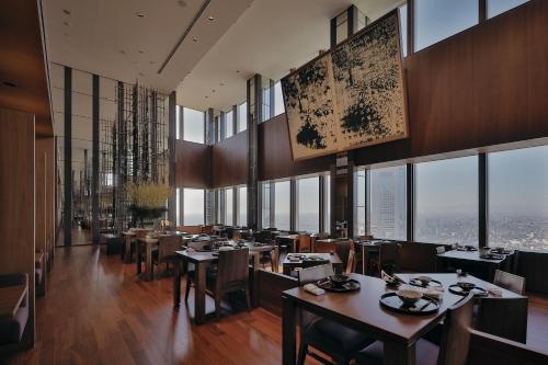 a restaurant with tables and chairs and large windows at Park Hyatt Tokyo in Tokyo