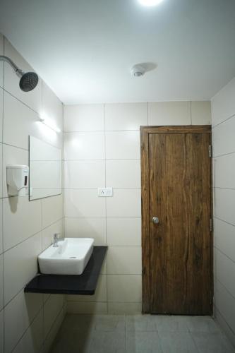 Hotel Kartiki في أورانغاباد: حمام مع حوض وباب خشبي