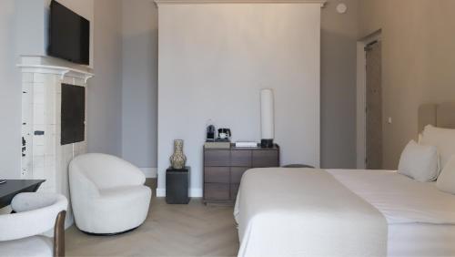 a white bedroom with a white bed and a chair at Dam Residence - Boutique Hotel in Zaandam