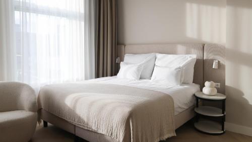 a bedroom with a bed with white sheets and a window at Dam Residence Boutique Hotel Amsterdam - Zaandam in Zaandam