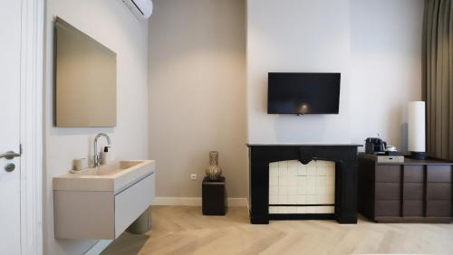 a bathroom with a sink and a tv above a fireplace at Dam Residence Boutique Hotel Amsterdam - Zaandam in Zaandam