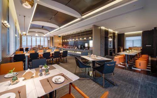 Un restaurante con mesas y sillas y un bar. en Arthur Hotel Baiyun Station Xinshixu Subway Station Guangzhou, en Guangzhou