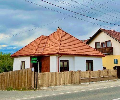 une maison avec un toit orange et une clôture en bois dans l'établissement Bálint Apartman 1, à Valea Strîmbă