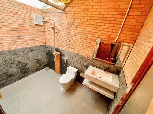 a bathroom with a toilet and a sink and a brick wall at Nam Cat Tien Retreat in Tân Phú