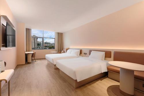 a hotel room with two beds and a table at Hanting Hotel Chongqing Lianglukou Caiyuanba in Chongqing