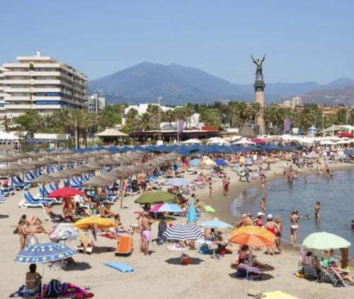 una multitud de personas en una playa con sombrillas en Apartamento moderno Centro de Marbella, en Marbella