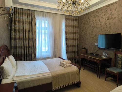 a bedroom with a bed and a desk and a television at Antique Royal Hotel in Baku