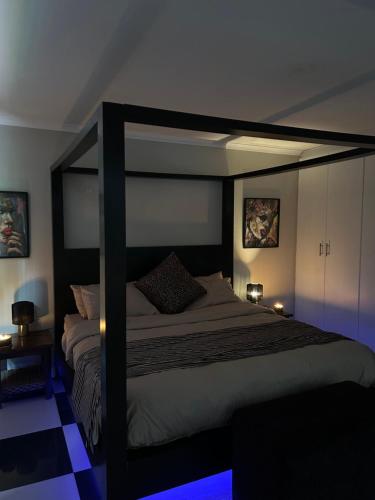 a bedroom with a large bed with a black canopy at Innessfree Cottage in Doordrift