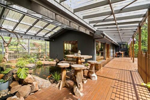 a patio with a pond and wooden tables and stools at Tranquill 4BR Retreat in Sassafras