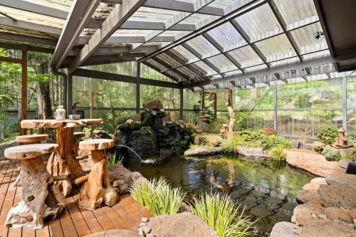 a glass greenhouse with a pond in a garden at Tranquill 4BR Retreat in Sassafras
