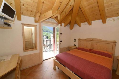 a bedroom with a bed and a large window at Garni La Genziana in Temù