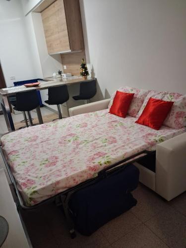 a bed in a living room with red pillows on it at Bilocale comodamente collegato con centro Milano in Garbagnate Milanese