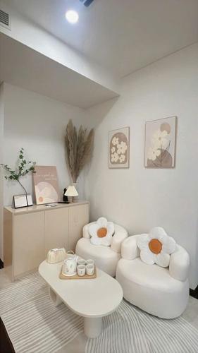 a living room with two white chairs and a coffee table at Gia An Homestay in Phú Thú