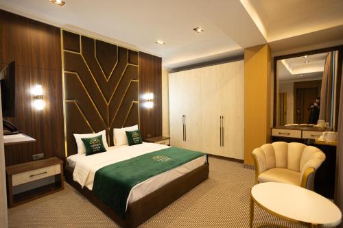 Una habitación de hotel con una cama, una mesa y una silla. en Green Park Hotel, en Shymkent