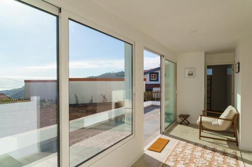 a room with glass doors and a balcony with a chair at GuestReady - Hillside Escape I in Câmara de Lobos