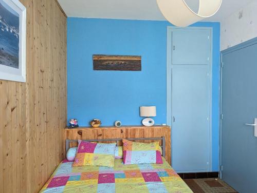 a bedroom with a bed with a blue wall at Villa 100m plage in La Faute-sur-Mer