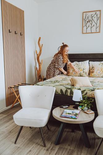 a woman sitting on a bed in a room at Bed & Breakfast Het Vinkenest Nijverdal in Nijverdal