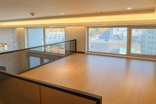 Magnum Nampo Hotel في Jung-gu: غرفة فارغة مع أرضية خشبية ونوافذ كبيرة