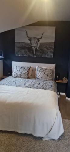 een slaapkamer met een wit bed met een schilderij aan de muur bij Chez Isa in Malmedy