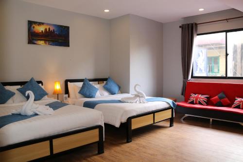 a bedroom with two beds and a red couch at Ostro Hotel in Phnom Penh