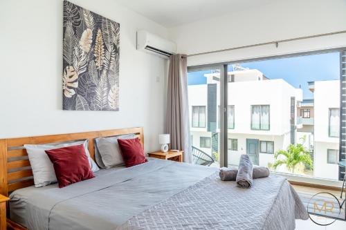 a bedroom with a bed and a large window at Azure 4 Bedrooms Haven Retreat: Where Tranquility Meets Turquoise Waters, Flic en Flac Mauritius in Flic-en-Flac
