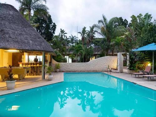 a swimming pool at a resort with a thatch roof at St. Lucia Safari Lodge in St Lucia
