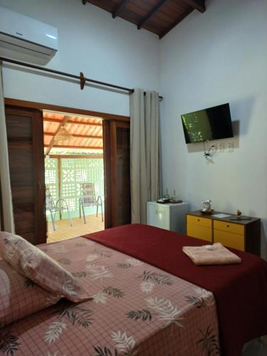 Schlafzimmer mit einem Bett, einem TV und einer Terrasse in der Unterkunft Cafofo de Dri in Ilha de Boipeba
