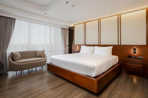 a bedroom with a large bed and a chair at oneTree Plaza Hotel Cebu in Cebu City