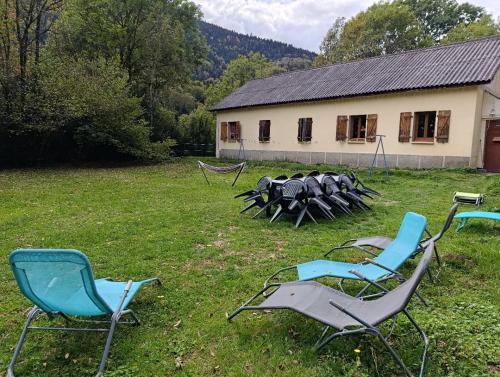 a group of chairs sitting in the grass in front of a building at Gîte Espace et Montagne in Aragnouet